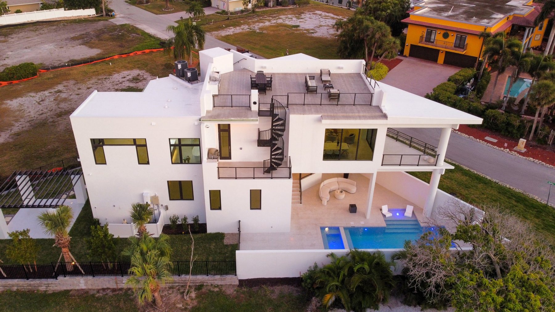 Aerial from behind: rooftop terrace, spiral stair, covered terrace and pool